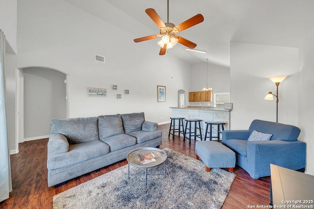 living room with arched walkways, dark wood finished floors, visible vents, a ceiling fan, and high vaulted ceiling