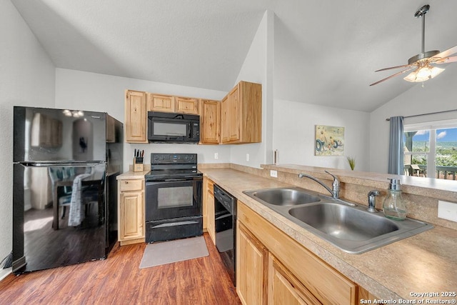 kitchen featuring lofted ceiling, light brown cabinets, a sink, wood finished floors, and black appliances