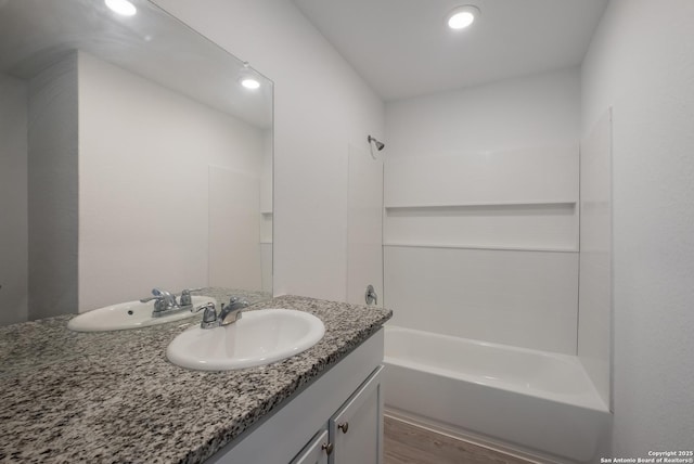 bathroom with recessed lighting, bathtub / shower combination, vanity, and wood finished floors