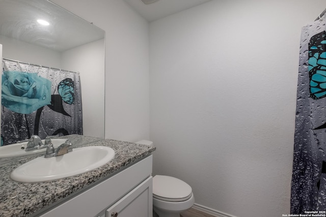 full bath with toilet, vanity, and baseboards