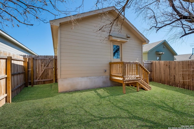 rear view of house featuring a lawn, a fenced backyard, and a gate