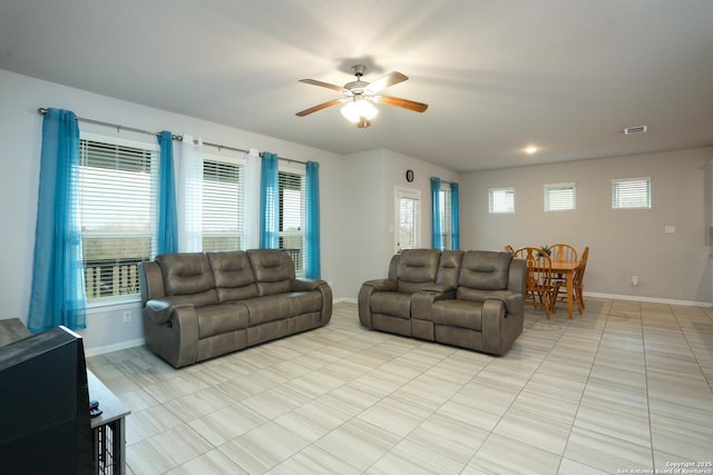 living room featuring light tile patterned floors, a ceiling fan, visible vents, and baseboards