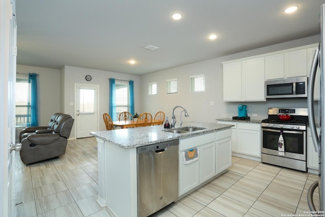 kitchen featuring a sink, visible vents, white cabinetry, open floor plan, and appliances with stainless steel finishes