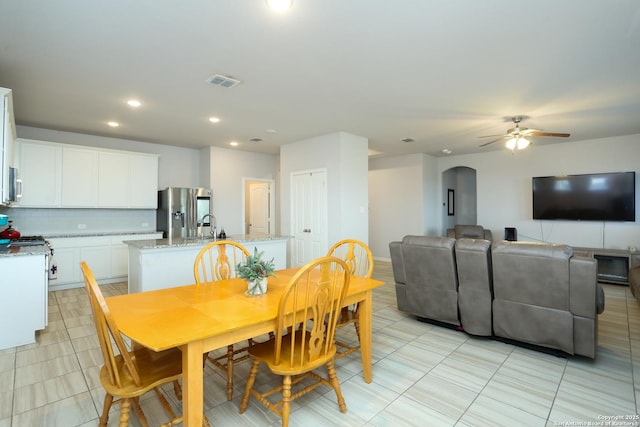 dining space with light tile patterned floors, visible vents, arched walkways, a ceiling fan, and recessed lighting