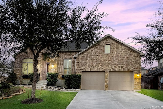 view of front of home with concrete driveway, a lawn, stone siding, an attached garage, and brick siding