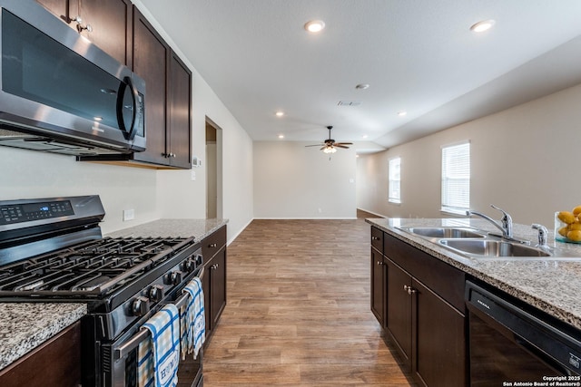 kitchen with stainless steel appliances, a sink, a ceiling fan, dark brown cabinets, and light wood-type flooring