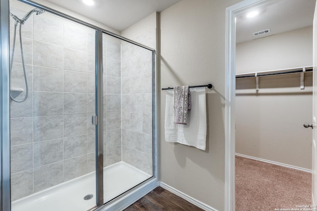 bathroom with a stall shower, a walk in closet, visible vents, and baseboards