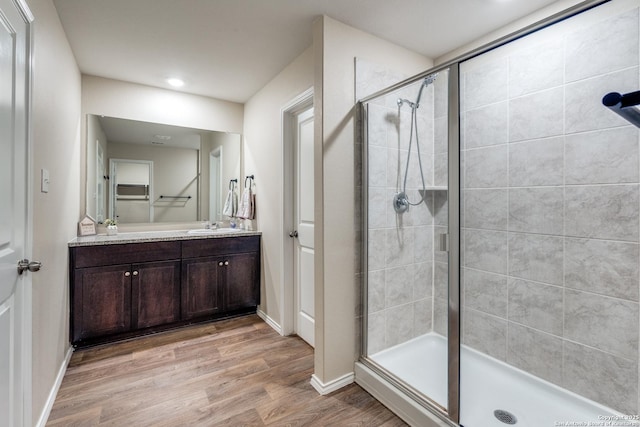 bathroom with a stall shower, baseboards, wood finished floors, and vanity