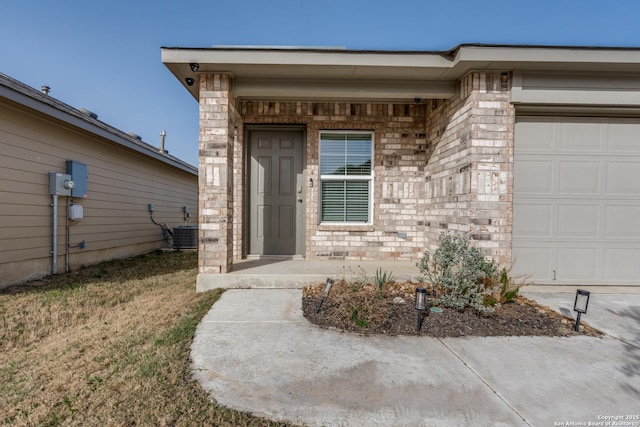 entrance to property featuring a garage, central AC unit, and brick siding