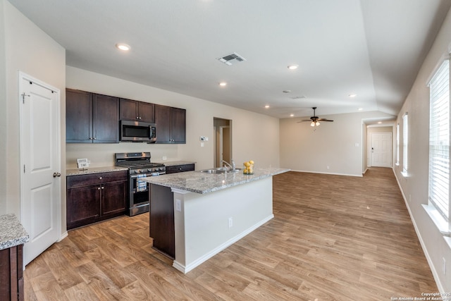 kitchen with visible vents, stainless steel appliances, dark brown cabinets, light wood-type flooring, and a sink