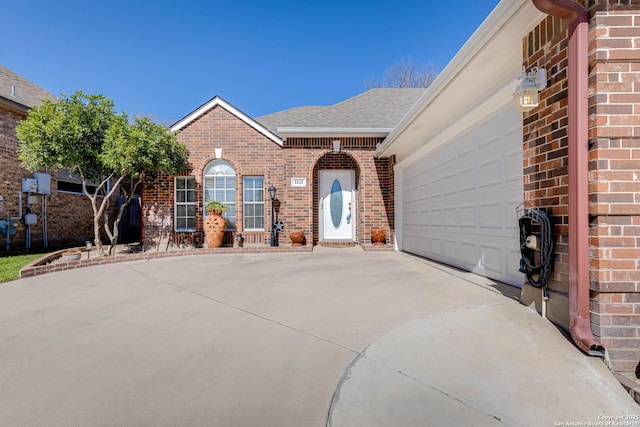 view of front facade featuring driveway, brick siding, and an attached garage