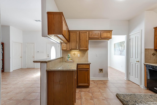 kitchen featuring light stone counters, light tile patterned flooring, brown cabinets, dishwasher, and tasteful backsplash