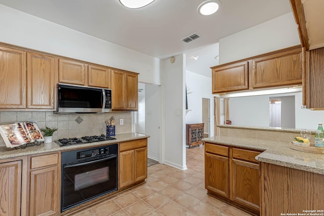 kitchen featuring visible vents, decorative backsplash, stainless steel microwave, gas stovetop, and black oven