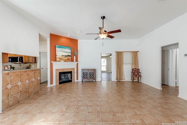 living room featuring light tile patterned flooring, ceiling fan, and a tiled fireplace