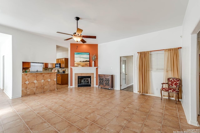 unfurnished living room featuring ceiling fan, light tile patterned floors, and a tiled fireplace