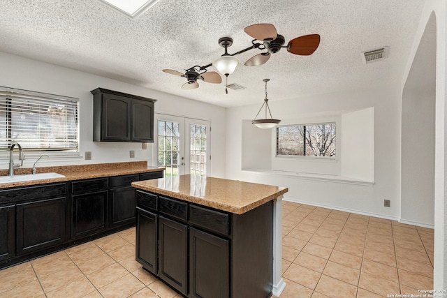 kitchen with french doors, light tile patterned floors, a ceiling fan, a sink, and dark cabinetry