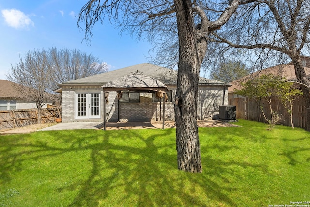 back of house featuring french doors, a patio, a fenced backyard, a yard, and brick siding