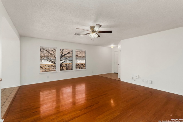 unfurnished room featuring visible vents, ceiling fan, a textured ceiling, wood finished floors, and baseboards