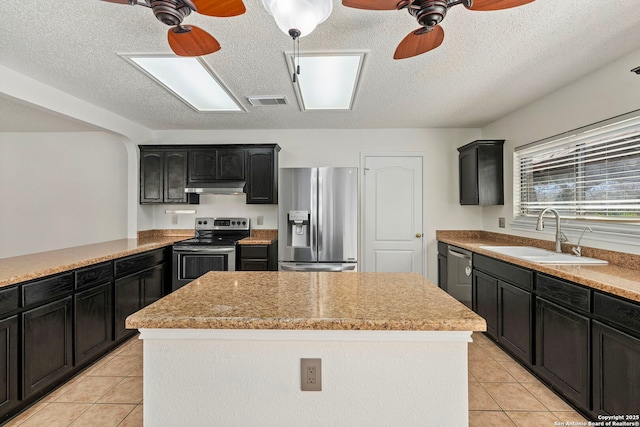 kitchen with ceiling fan, under cabinet range hood, a kitchen island, a sink, and appliances with stainless steel finishes