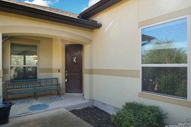 view of exterior entry featuring a porch and stucco siding