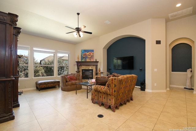 living area featuring lofted ceiling, ceiling fan, light tile patterned flooring, baseboards, and a glass covered fireplace