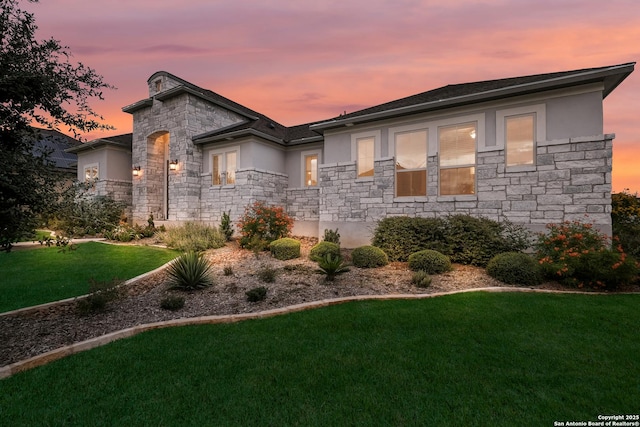 view of front facade with stone siding, a front yard, and stucco siding