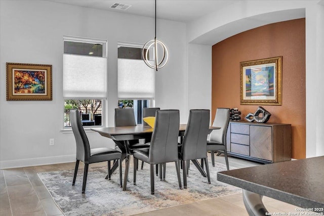 dining room featuring arched walkways, visible vents, and baseboards