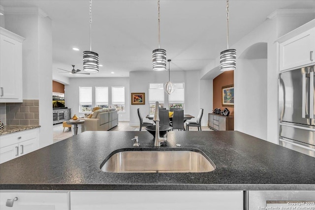 kitchen featuring a ceiling fan, freestanding refrigerator, white cabinets, and decorative backsplash