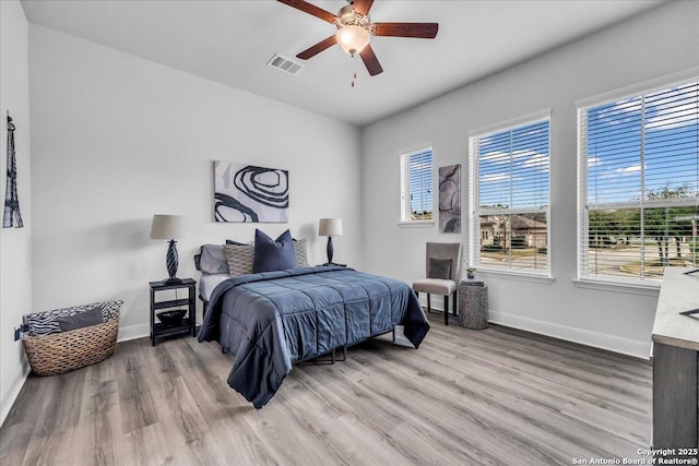 bedroom featuring baseboards, visible vents, ceiling fan, and wood finished floors