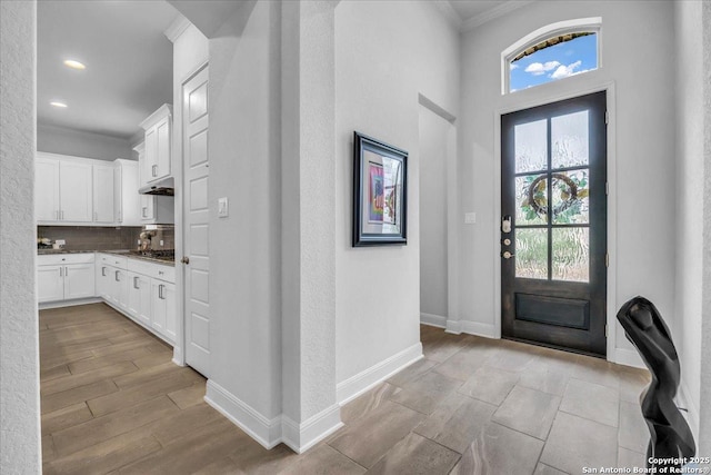 foyer entrance with light wood-type flooring, baseboards, crown molding, and recessed lighting