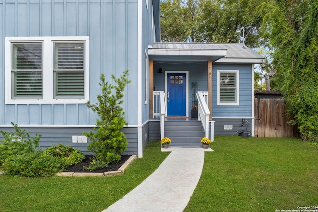 view of exterior entry featuring board and batten siding, crawl space, fence, and a lawn