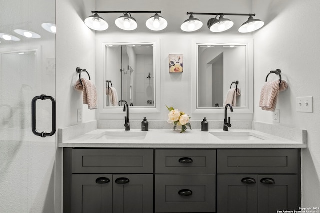 full bathroom with a sink, a shower stall, and double vanity