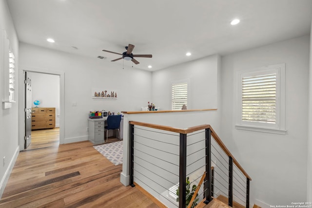 hall with light wood finished floors, visible vents, baseboards, an upstairs landing, and recessed lighting