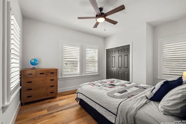 bedroom with a ceiling fan, a closet, light wood-style flooring, and baseboards