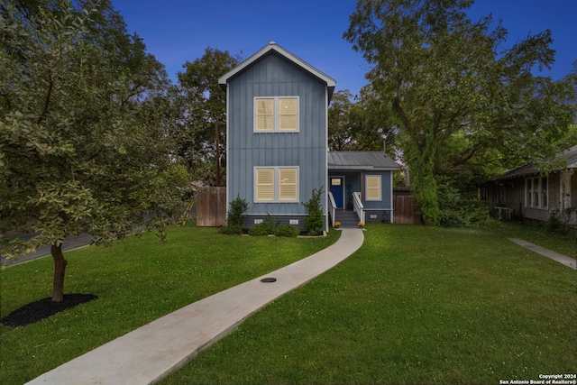 view of front of property with board and batten siding, a front yard, crawl space, and fence