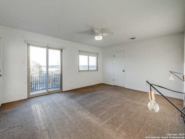 carpeted spare room with baseboards, visible vents, and a ceiling fan