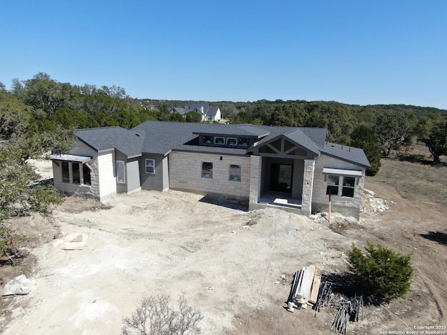 property in mid-construction with stone siding and a view of trees