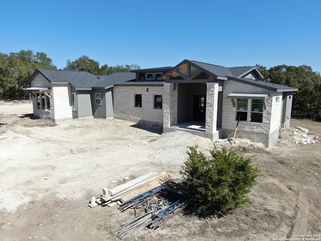 property under construction with a shingled roof and stone siding