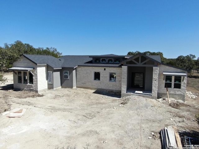 view of front of house with stone siding and roof with shingles