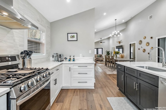 kitchen with light wood finished floors, visible vents, appliances with stainless steel finishes, a sink, and wall chimney exhaust hood