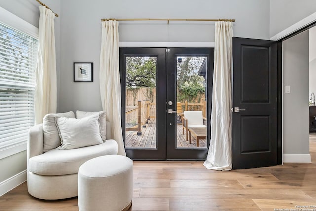 doorway with french doors, baseboards, and wood finished floors