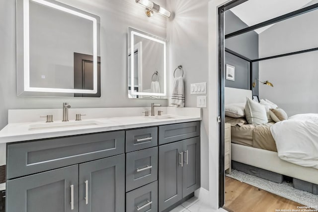 full bath with wood finished floors, double vanity, a sink, and ensuite bathroom