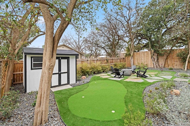 view of yard with a storage shed, a fenced backyard, a patio, and an outdoor structure