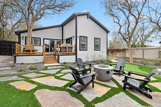 back of property with fence, a fire pit, a wooden deck, and a patio