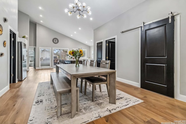 dining room with light wood-style floors, baseboards, an inviting chandelier, and a barn door