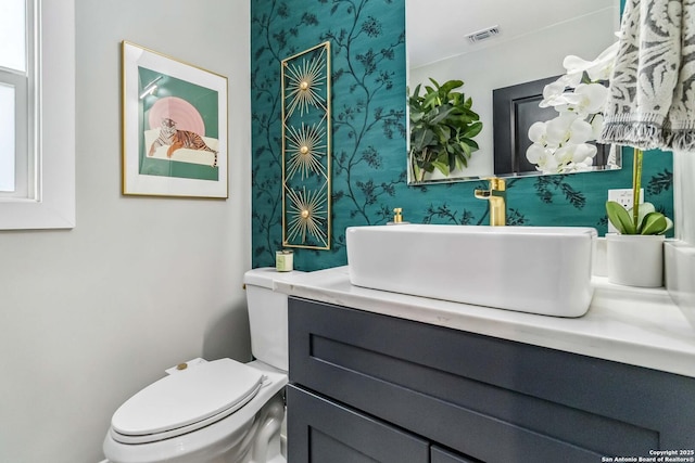 half bath featuring visible vents, vanity, and toilet