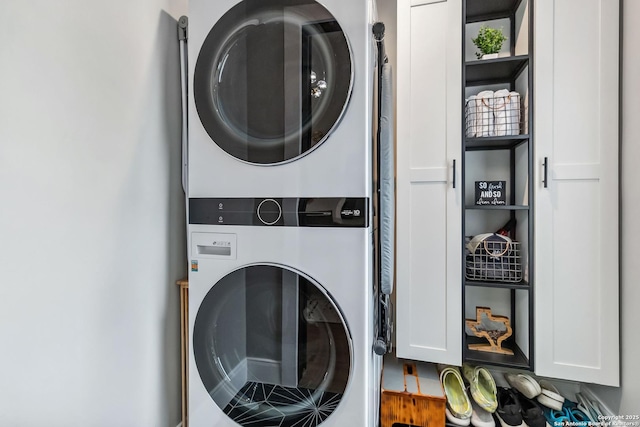 washroom with stacked washer / dryer and cabinet space