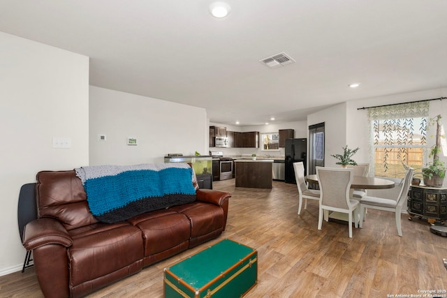 living room featuring light wood-style floors, baseboards, visible vents, and recessed lighting