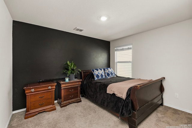 bedroom with baseboards, visible vents, and light colored carpet