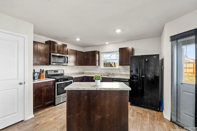 kitchen featuring dark brown cabinetry, a sink, a center island, black appliances, and light wood finished floors